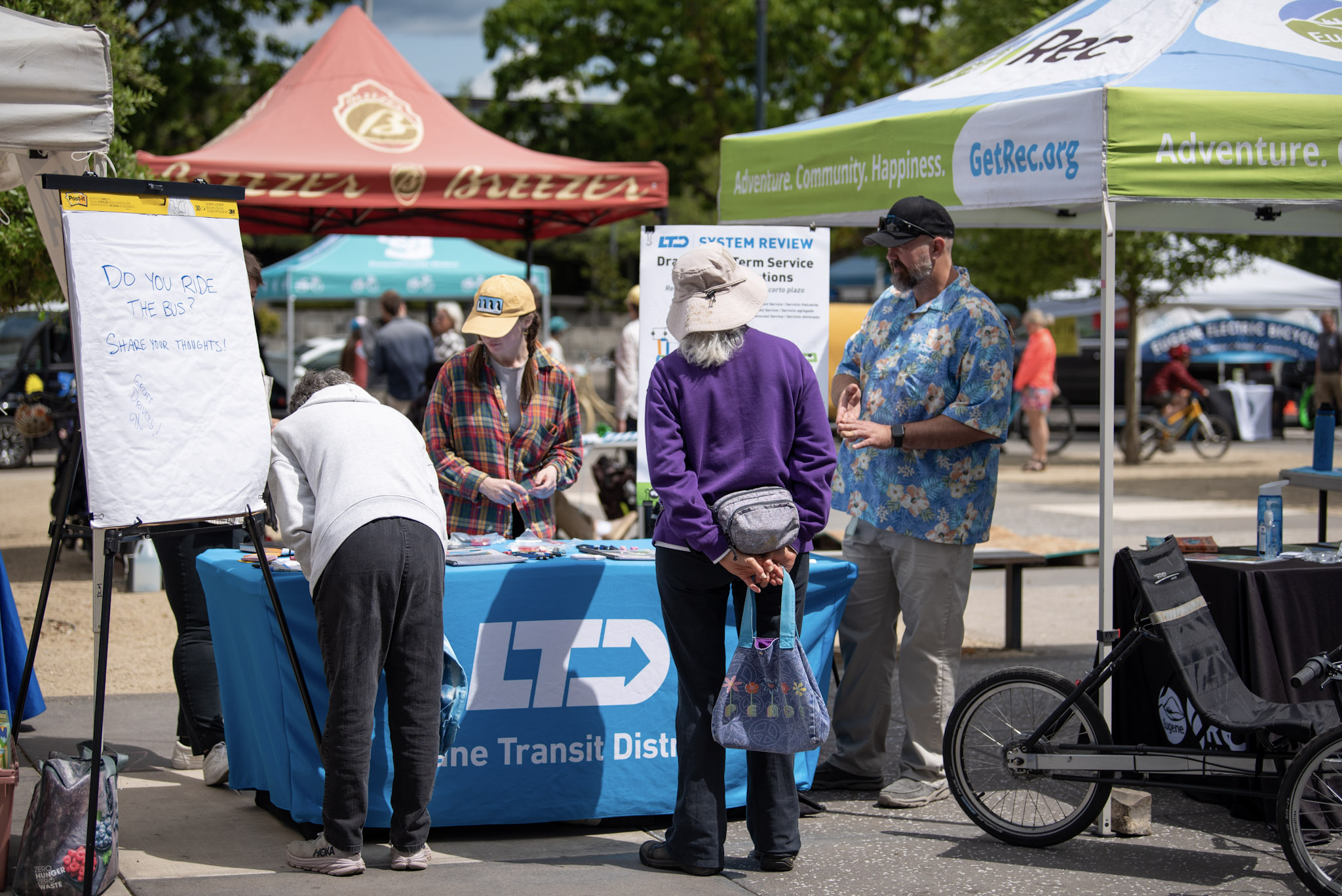 A group of community members stop by a table for information and to engage with Lane Transit.