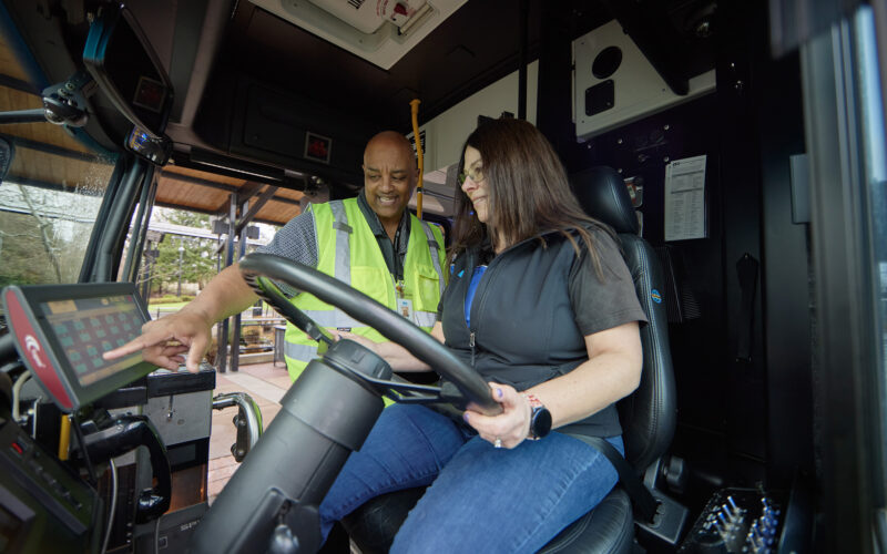 one person training another person how to drive a bus