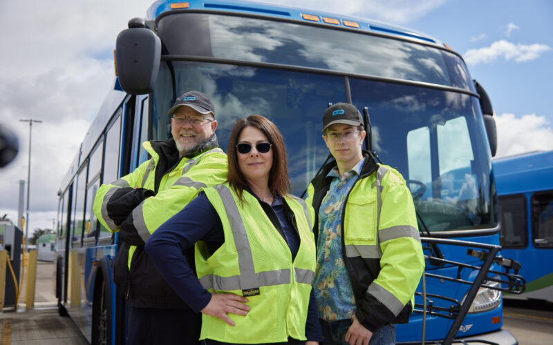 three people standing in front of bus