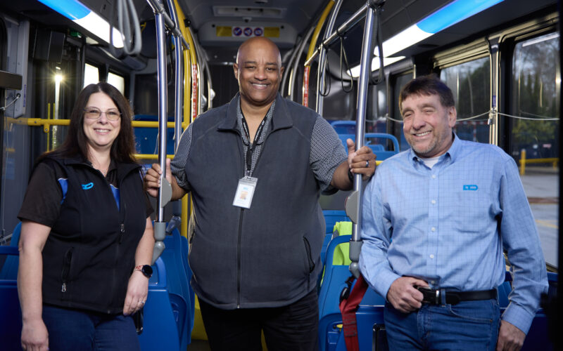 three employees standing inside a bus